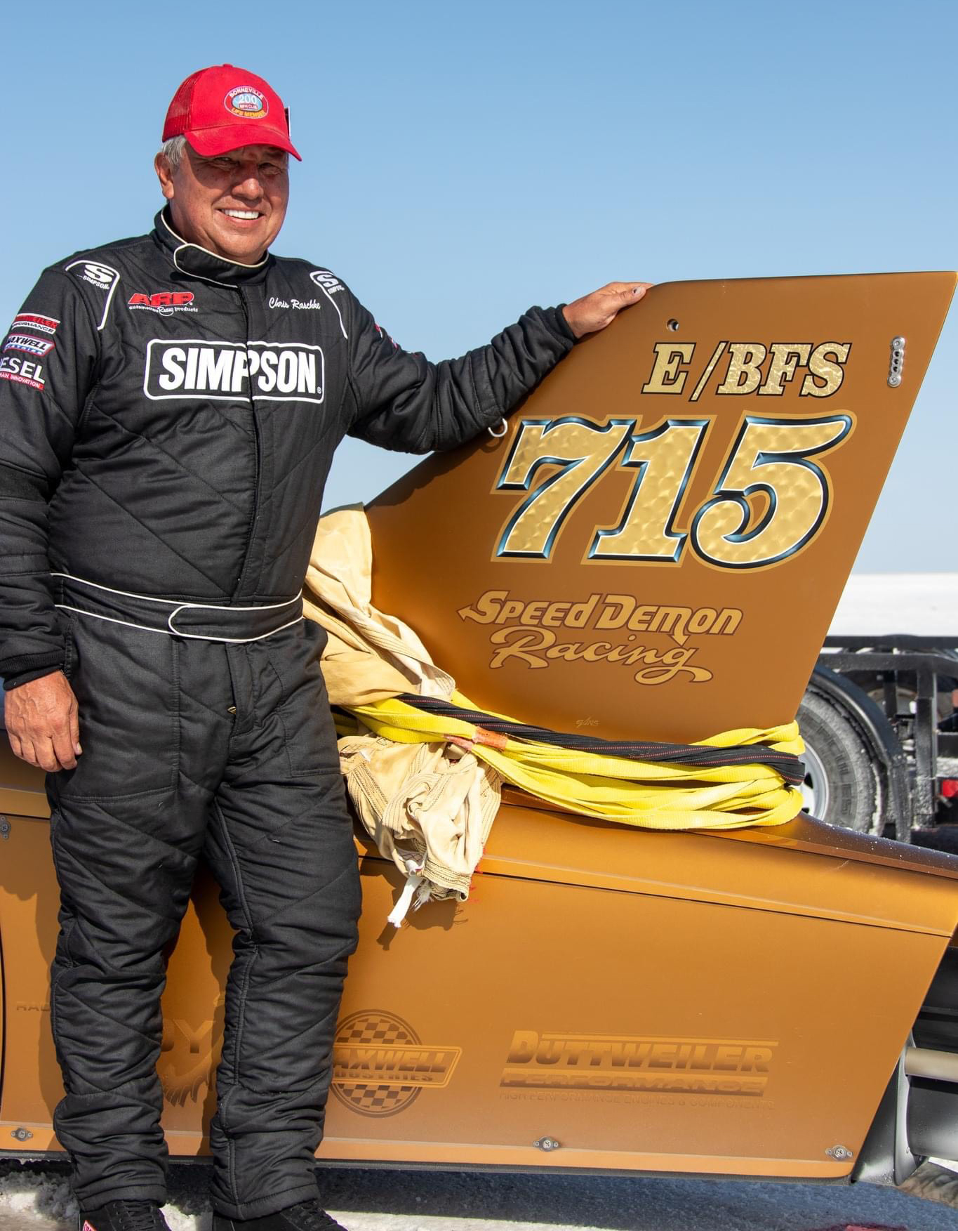 A photo of Chris Raschke standing next to the Speed Demon land speed racer.