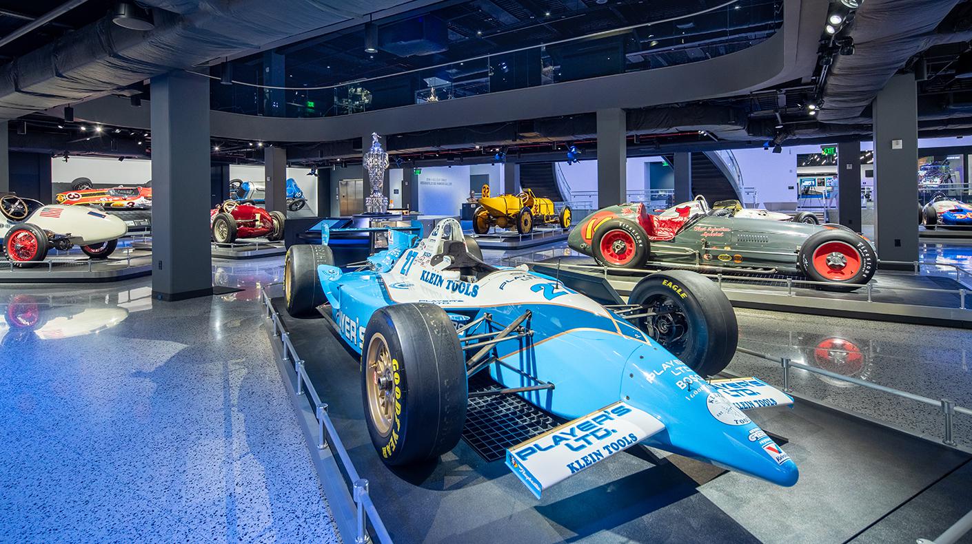A variety of Indy cars from various eras inside the IMS Museum gallery.
