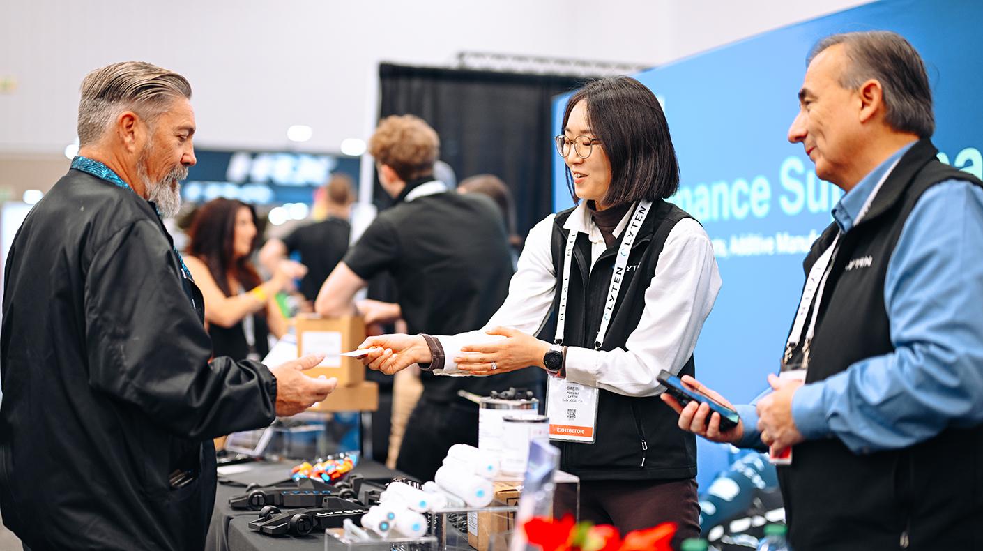 PRI Show exhibitors talking about their products with a PRI Show attendee. 