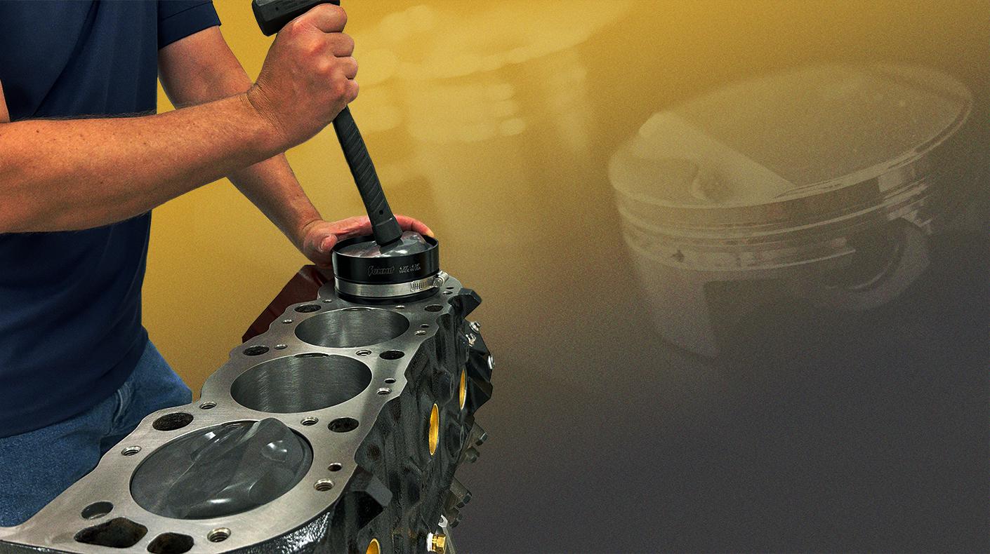 Engine builder inserting piston into cylinder.
