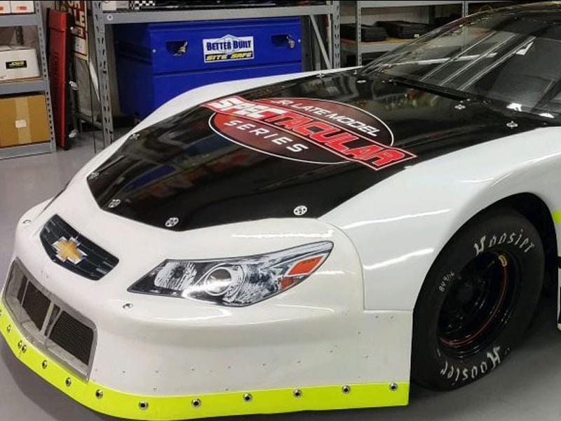 #21 race car with the Jr. Late Model Spectacular Series (JRLMSS) logo on the hood. In a garage setting
