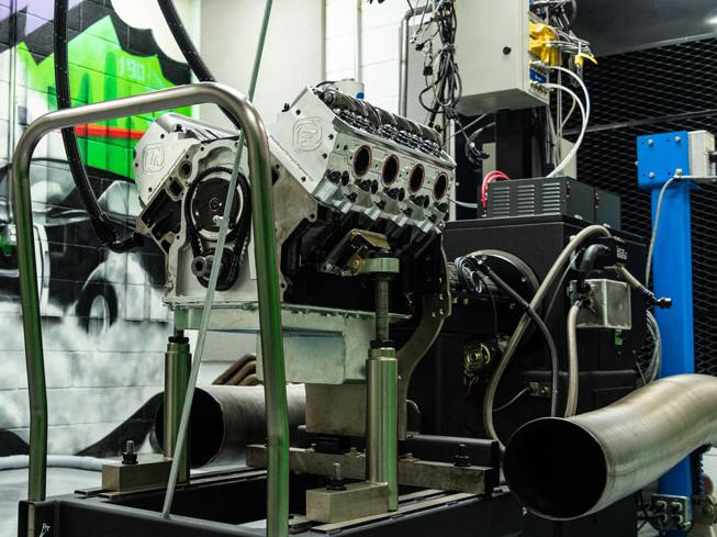 race engine hooked up to a dyno in the foreground, art mural on the wall of Frankenstein Engine Dynamics facility in the background