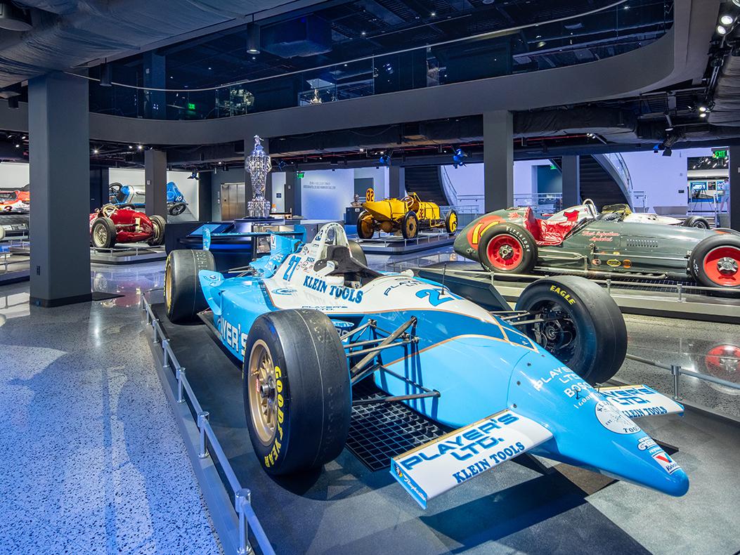 A variety of Indy cars from various eras inside the IMS Museum gallery.
