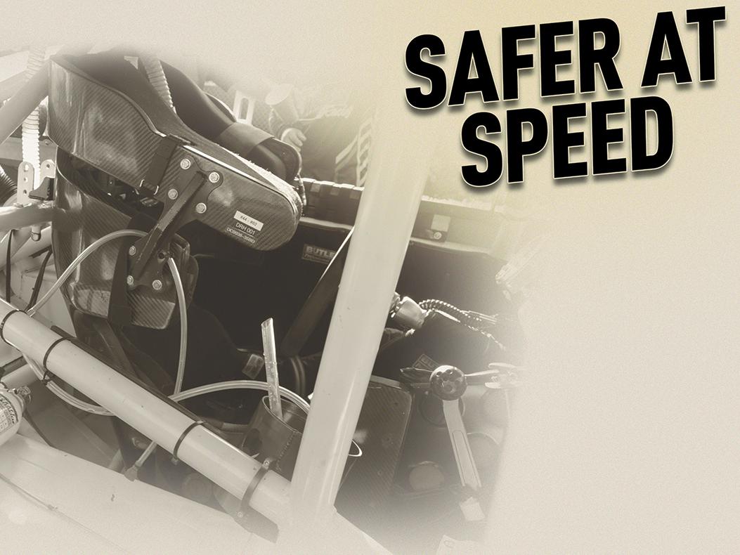 Inside of a stock car cockpit with the words "Safer at Speed" over the top.